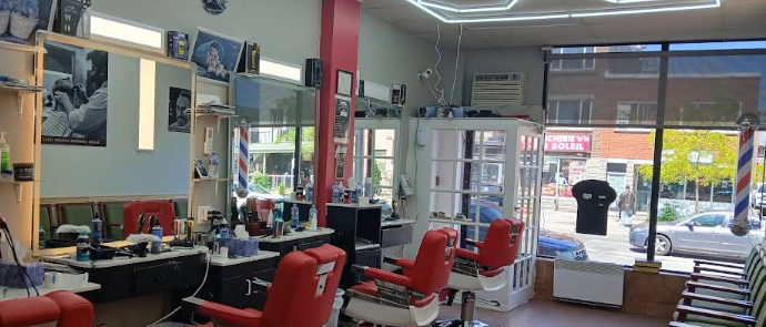 Intérieur du salon de coiffure Sahara : chaises rouges, miroirs et enseigne barber pole